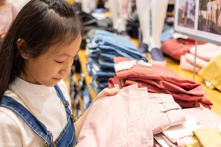 快乐的亚洲女孩选择服装商场或服装店, 销售和消费观念的概念照片